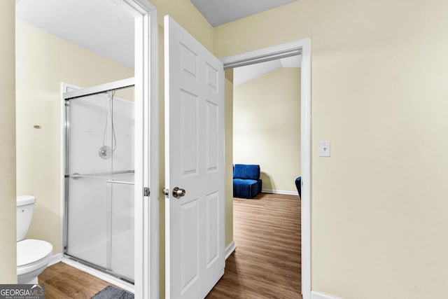 bathroom with an enclosed shower, toilet, and hardwood / wood-style floors