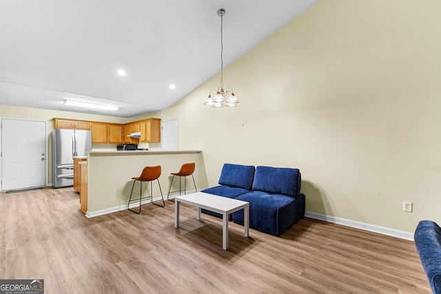 living room with light wood-type flooring, a chandelier, and vaulted ceiling