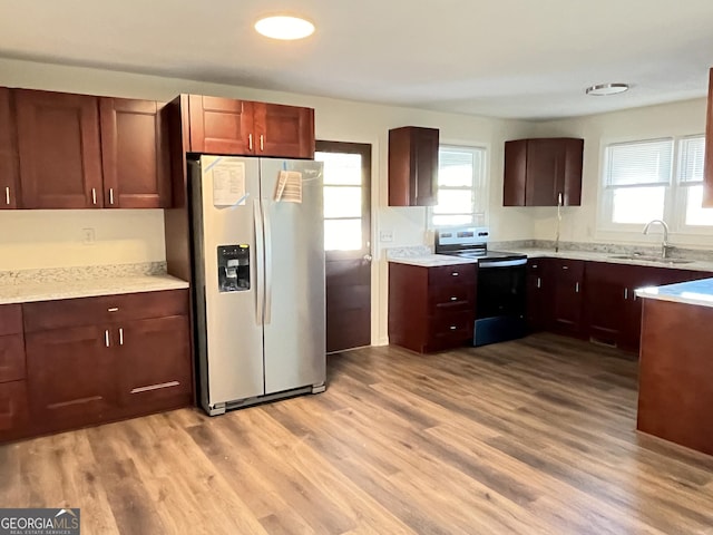 kitchen with sink, appliances with stainless steel finishes, and light hardwood / wood-style flooring