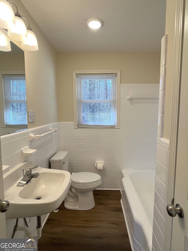 bathroom with toilet, hardwood / wood-style flooring, a bathtub, tile walls, and sink