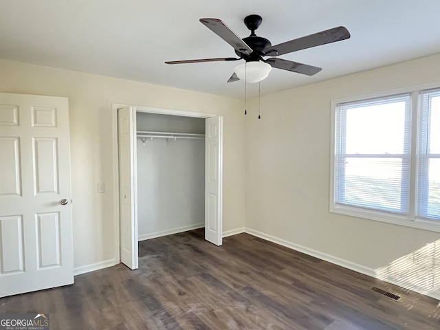 unfurnished bedroom with ceiling fan, a closet, and dark wood-type flooring