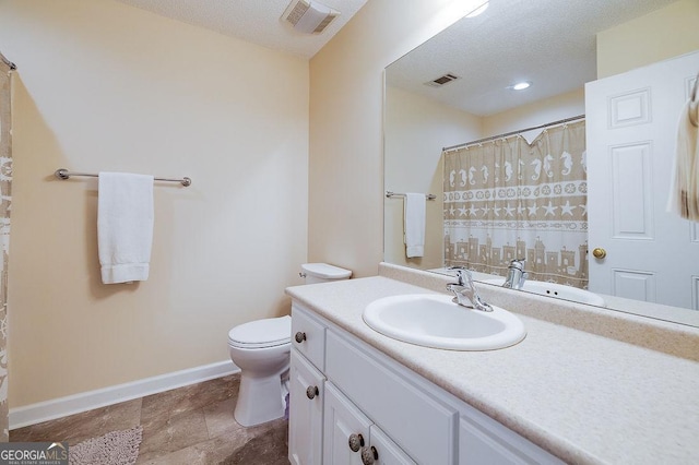 bathroom with a textured ceiling, toilet, and vanity