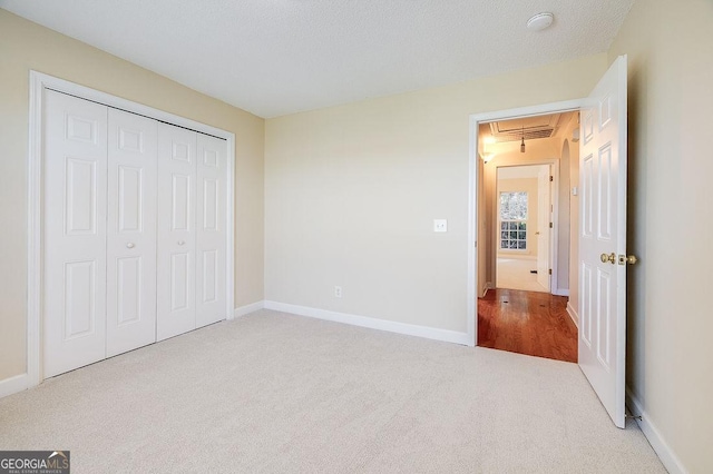 unfurnished bedroom with light colored carpet, a textured ceiling, and a closet