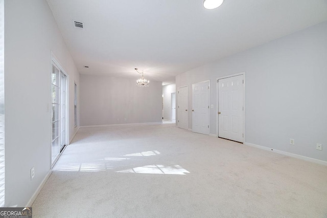 unfurnished room featuring light carpet and a notable chandelier