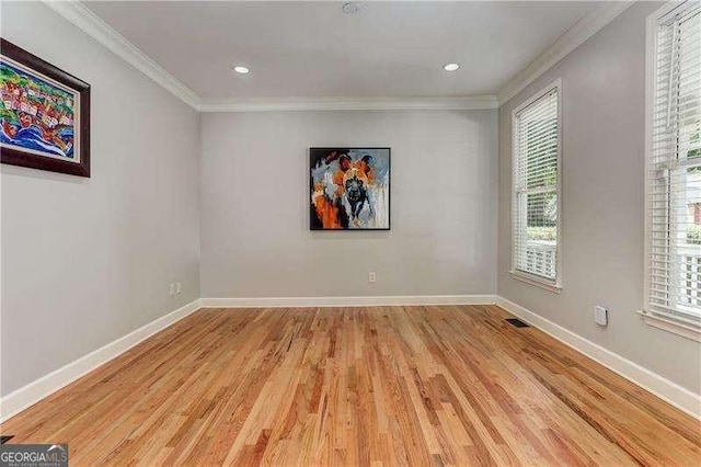 spare room with ornamental molding and light wood-type flooring