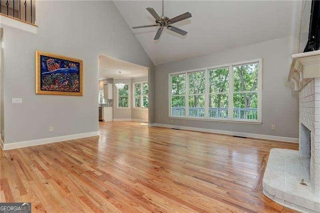 unfurnished living room featuring a brick fireplace, high vaulted ceiling, ceiling fan, and light wood-type flooring