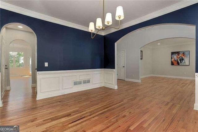 empty room featuring light wood-type flooring, an inviting chandelier, and crown molding