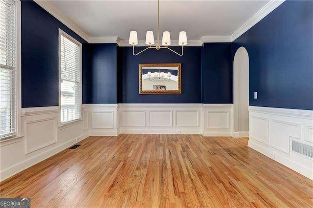 unfurnished dining area featuring crown molding, a chandelier, and light wood-type flooring