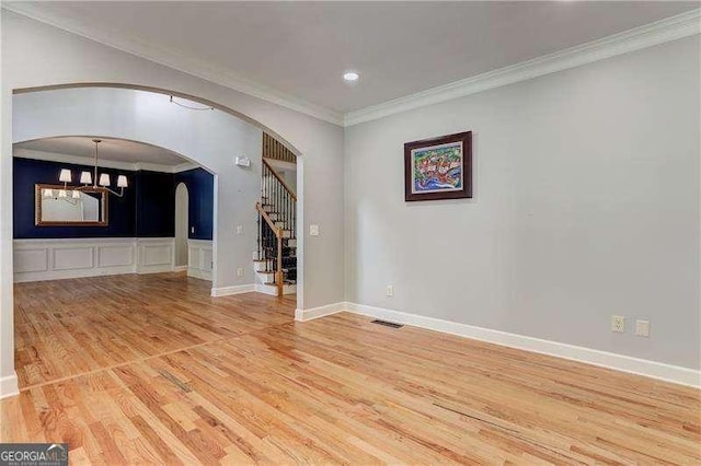 unfurnished living room with ornamental molding, hardwood / wood-style flooring, and a notable chandelier