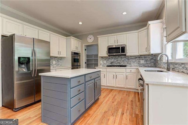 kitchen featuring white cabinets, appliances with stainless steel finishes, a center island, sink, and gray cabinetry