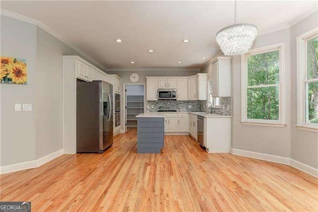 kitchen with white cabinets, appliances with stainless steel finishes, pendant lighting, and a kitchen island