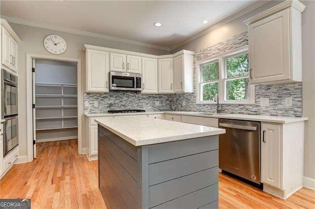 kitchen with white cabinetry, crown molding, a center island, and stainless steel appliances