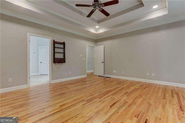 spare room with ornamental molding, light hardwood / wood-style floors, and a tray ceiling