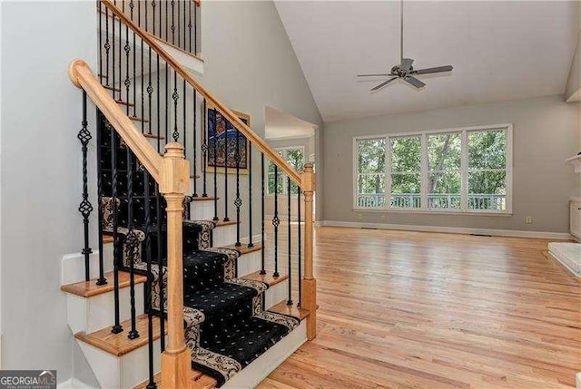 staircase with ceiling fan, vaulted ceiling, and hardwood / wood-style flooring