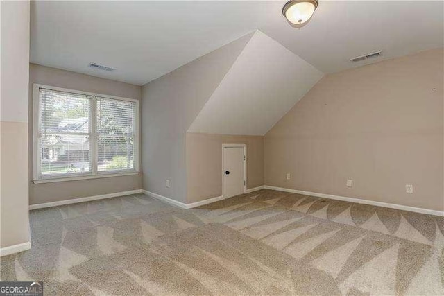 additional living space with light colored carpet and vaulted ceiling