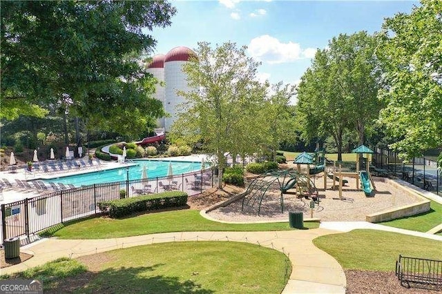 view of pool with a water slide, a playground, and a lawn