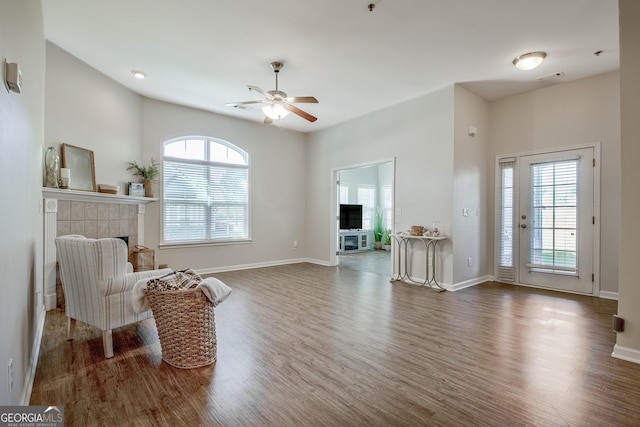 sitting room with ceiling fan, dark hardwood / wood-style flooring, a healthy amount of sunlight, and a fireplace