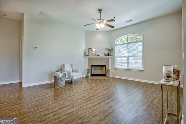 living area with ceiling fan, dark hardwood / wood-style flooring, and a fireplace