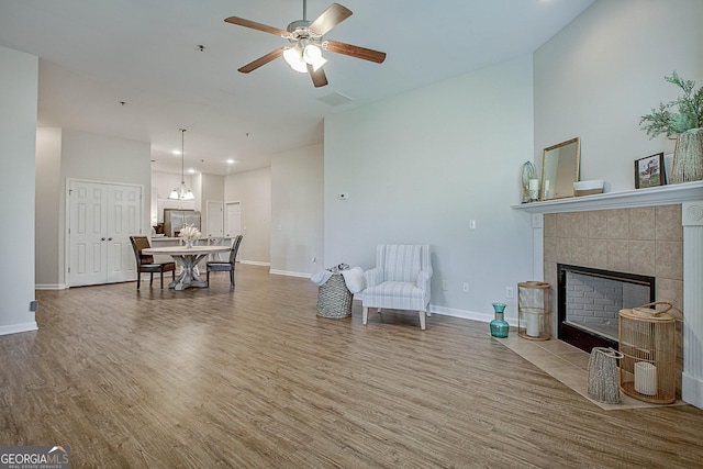 interior space with ceiling fan, wood-type flooring, and a tile fireplace