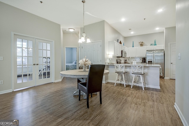 dining space featuring french doors, hardwood / wood-style floors, and a notable chandelier