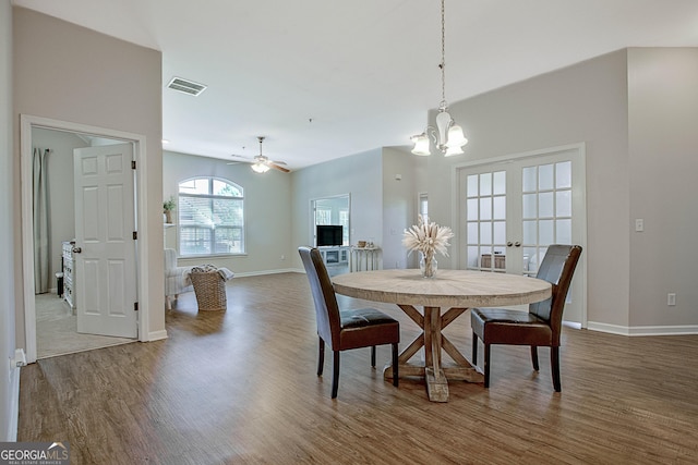 dining room featuring wood-type flooring, french doors, and ceiling fan with notable chandelier