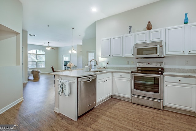 kitchen with white cabinets, appliances with stainless steel finishes, sink, hanging light fixtures, and kitchen peninsula