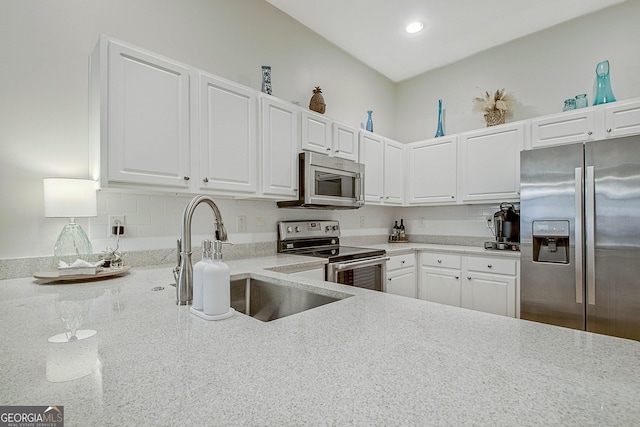 kitchen with light stone countertops, sink, white cabinets, and appliances with stainless steel finishes