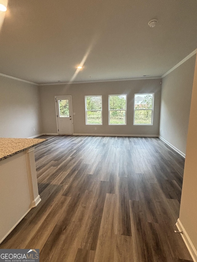 unfurnished living room featuring dark wood-type flooring, crown molding, and plenty of natural light