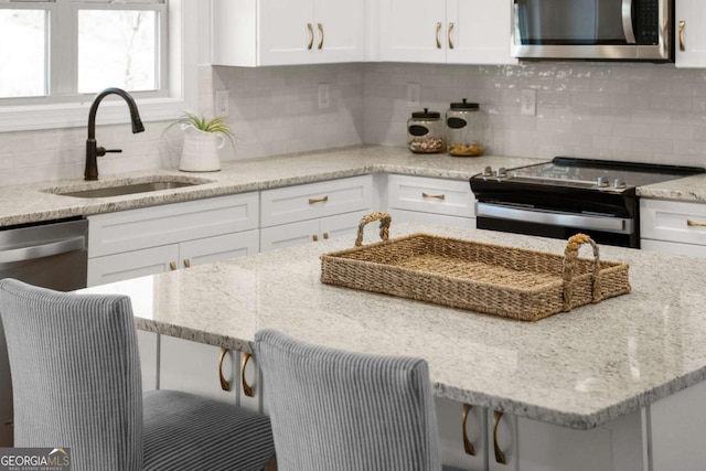 5721 Brickhampton Ct, Clermont, GA 30527 - kitchen featuring appliances with stainless steel finishes, white cabinetry, decorative backsplash, and light stone countertops