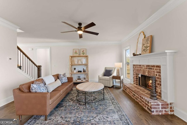 living room with ceiling fan, dark hardwood / wood-style flooring, crown molding, and a brick fireplace