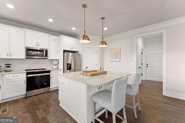 kitchen with stainless steel appliances, white cabinetry, a kitchen island, and decorative light fixtures