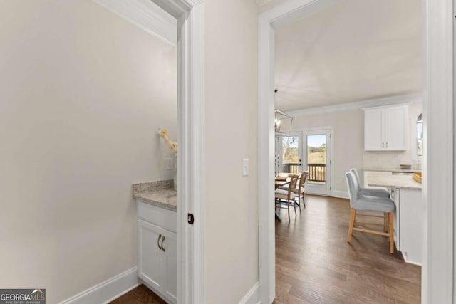 corridor with dark wood-type flooring and crown molding