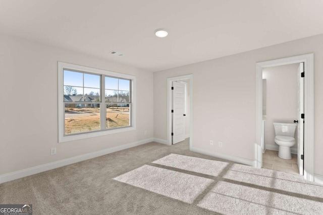 unfurnished bedroom with light colored carpet and connected bathroom