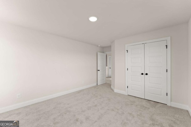 unfurnished bedroom with a closet and light carpet