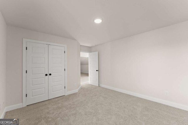 unfurnished bedroom with light colored carpet and a closet