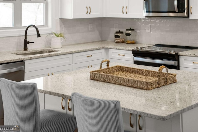 kitchen with decorative backsplash, sink, range with electric stovetop, white cabinets, and light stone counters