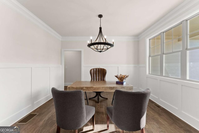 dining space featuring dark wood-type flooring, crown molding, and an inviting chandelier