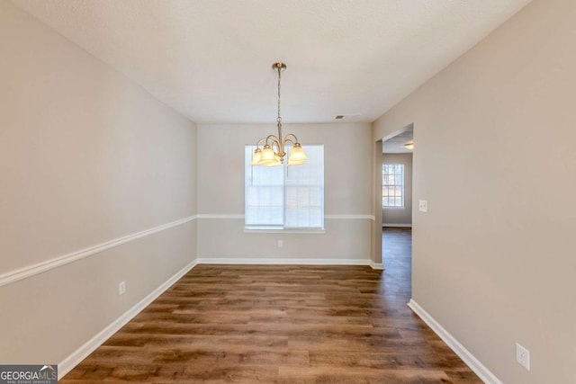 unfurnished dining area featuring dark hardwood / wood-style floors and an inviting chandelier