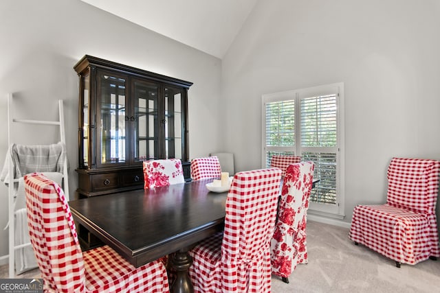 dining room with high vaulted ceiling and light colored carpet