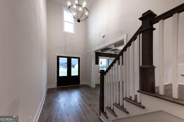 entryway with a high ceiling, a wealth of natural light, a notable chandelier, and french doors