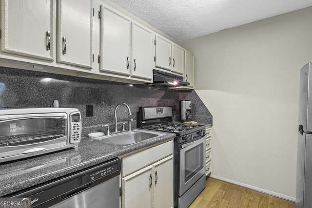 kitchen with a textured ceiling, appliances with stainless steel finishes, white cabinetry, light hardwood / wood-style floors, and sink