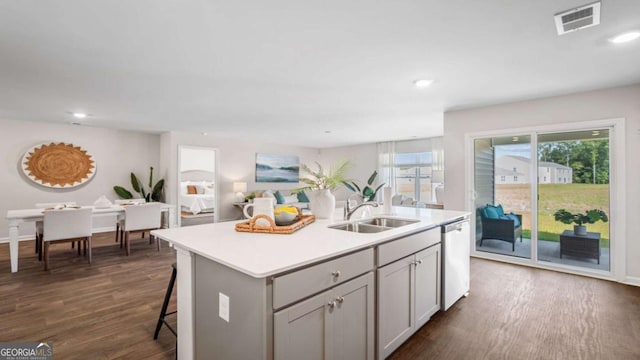 kitchen featuring dishwasher, sink, gray cabinets, a kitchen island with sink, and a breakfast bar