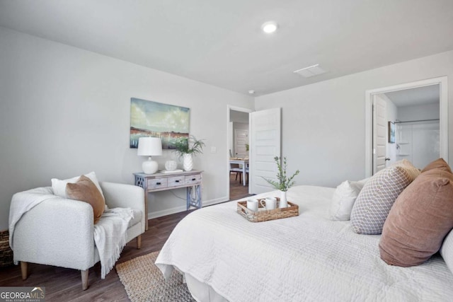 bedroom featuring ensuite bathroom and dark hardwood / wood-style flooring