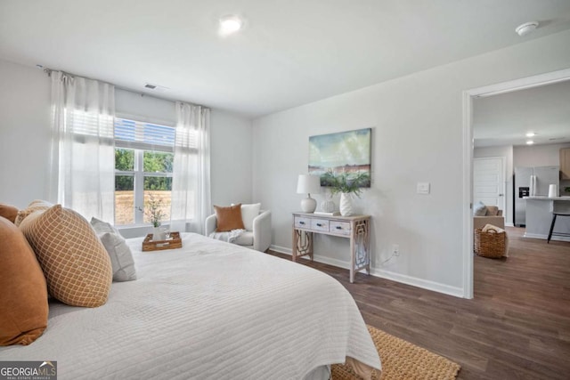 bedroom with stainless steel refrigerator with ice dispenser and dark wood-type flooring