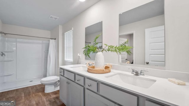 bathroom featuring toilet, a shower with shower curtain, hardwood / wood-style floors, and vanity