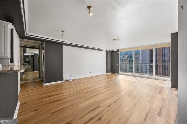 unfurnished living room with light wood finished floors and floor to ceiling windows