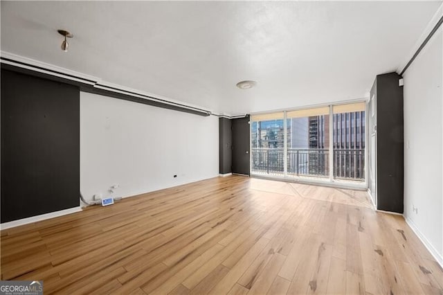 unfurnished living room featuring light wood-style floors, expansive windows, and baseboards