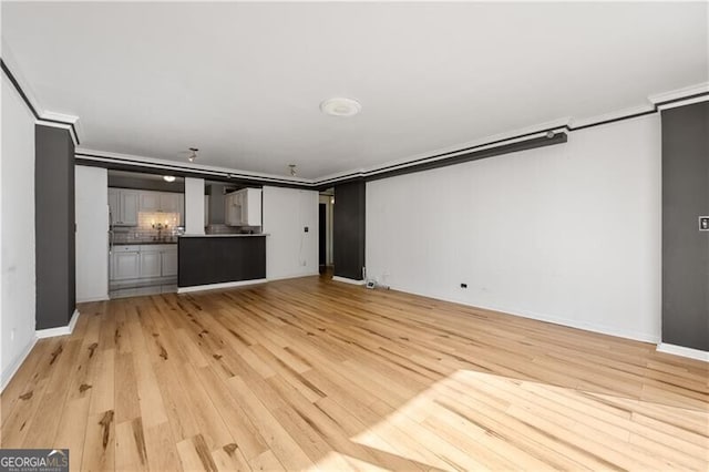 unfurnished living room featuring light wood-type flooring, baseboards, and ornamental molding