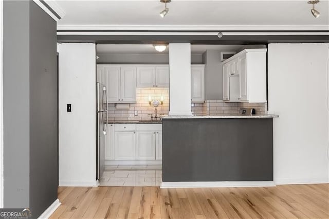 kitchen with tasteful backsplash, freestanding refrigerator, and white cabinetry