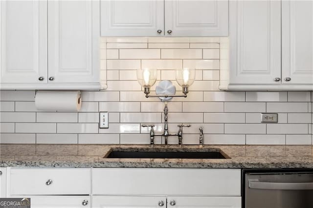 kitchen featuring tasteful backsplash, white cabinetry, dishwasher, and light stone countertops